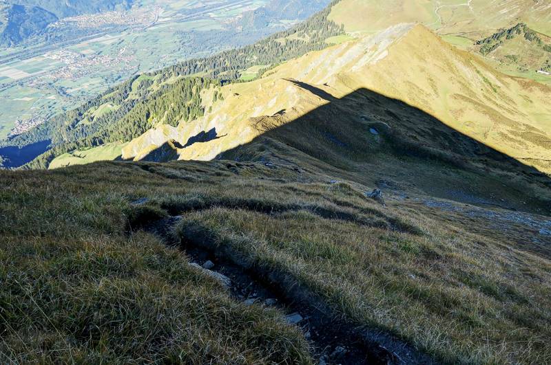 Der Wanderweg auf dem steilen Hang verläuft im kühlen Schatten von