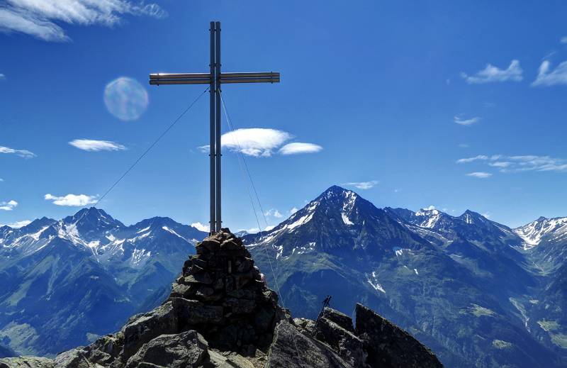 Das Gipfelkruez von Sunnig Grat mit Windgällen und Bristen im Hintergrund